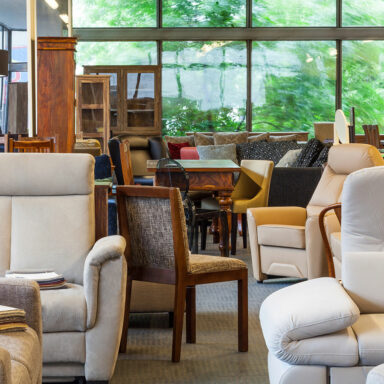 Verschiedene Möbelstücke wie Sessel, Stühle und Tische stehen ordentlich in einem Raum, vorbereitet zur Weiterverwendung, Lagerung oder Entsorgung nach einer Haushaltsauflösung.