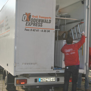 Umzugshelfer laden Möbel und Haushaltsgeräte in einen weißen Transporter