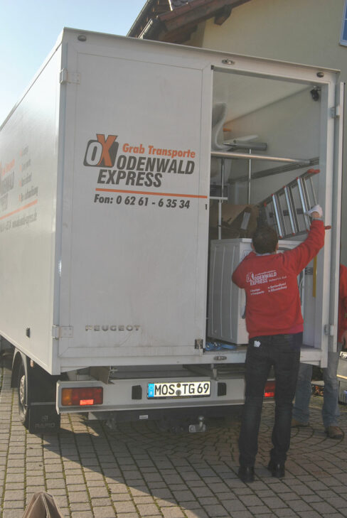 Umzugshelfer laden Möbel und Haushaltsgeräte in einen weißen Transporter