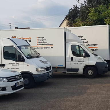 Mehrere Transportfahrzeuge des Unternehmens ‚Odenwald Express – Grab Transporte‘ stehen nebeneinander auf einem Parkplatz, bereit für Umzüge und Transporte