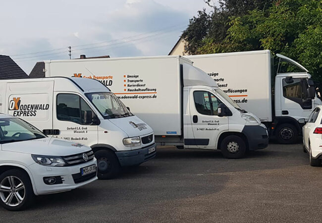 Mehrere Transportfahrzeuge des Unternehmens ‚Odenwald Express – Grab Transporte‘ stehen nebeneinander auf einem Parkplatz, bereit für Umzüge und Transporte